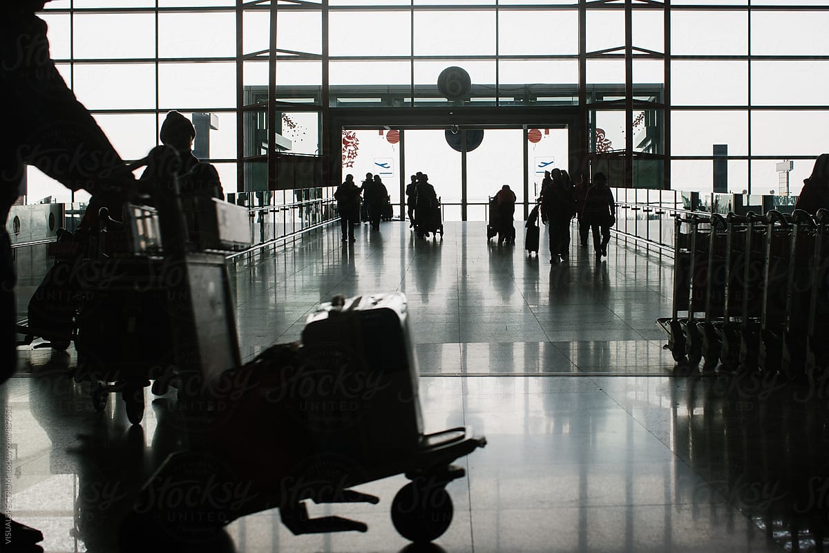 Silhouette of Travelers with Luggage in Airport