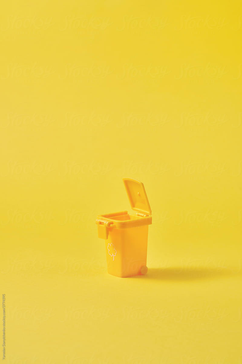 Small open yellow trash can on yellow background