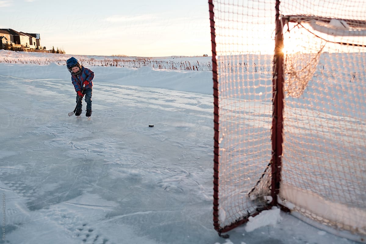 A toddler shooting the puck at the net