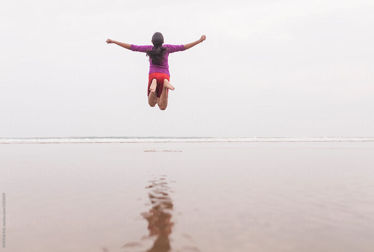 Teenage girl jumping in the air and making fun in a sea beach