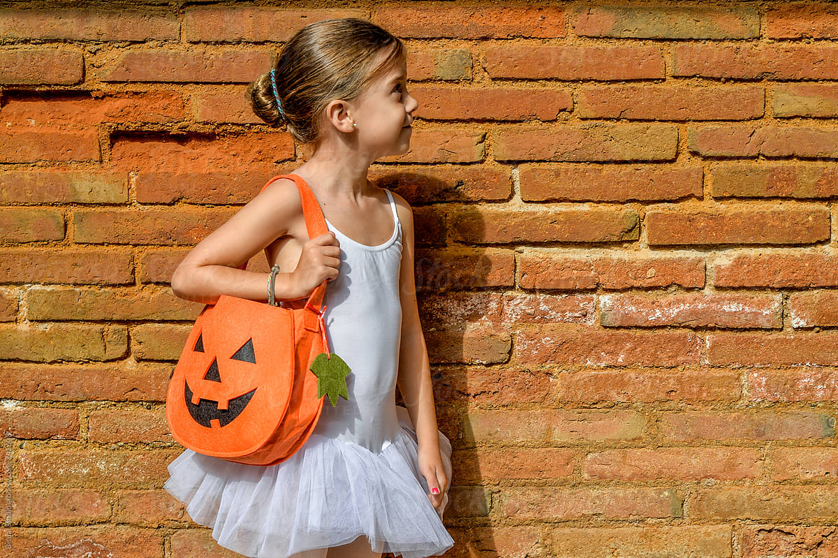 Little girl wearing a ballerina costume and a Halloween bag