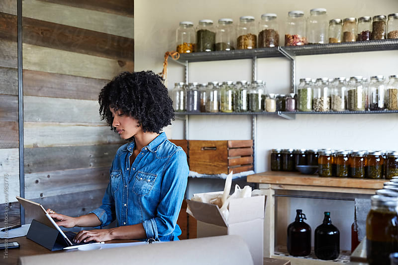 Millennial African American Woman businesswoman on computer in her skincare studio