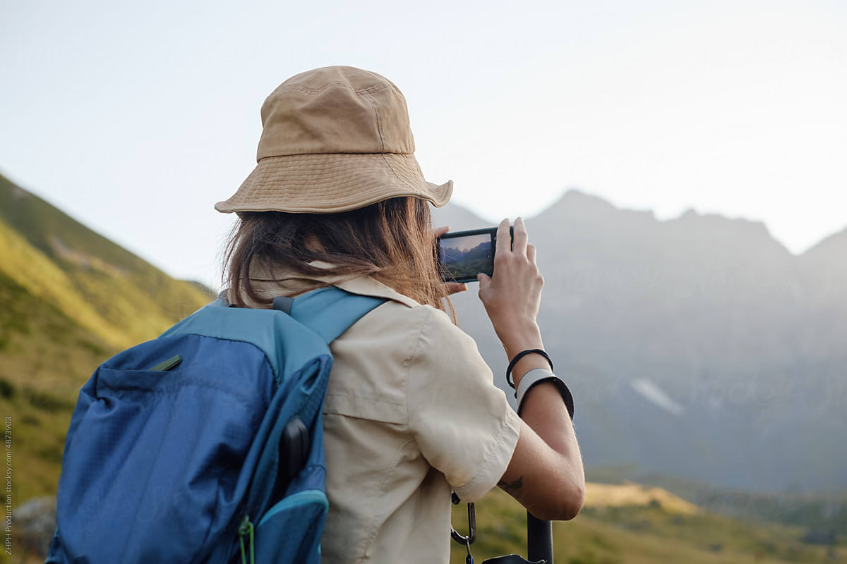 Woman hikes in the mountain area making photo with smartphone