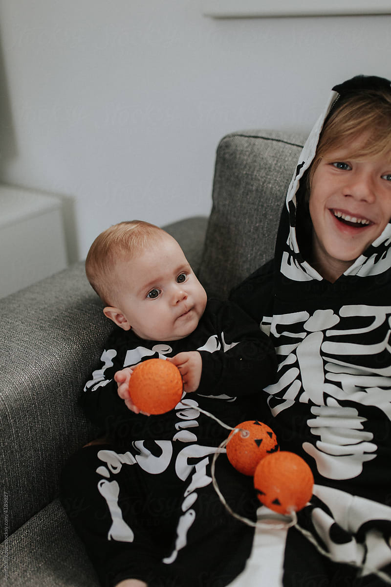 Laughing happy young boy celebrating Halloween with baby brother