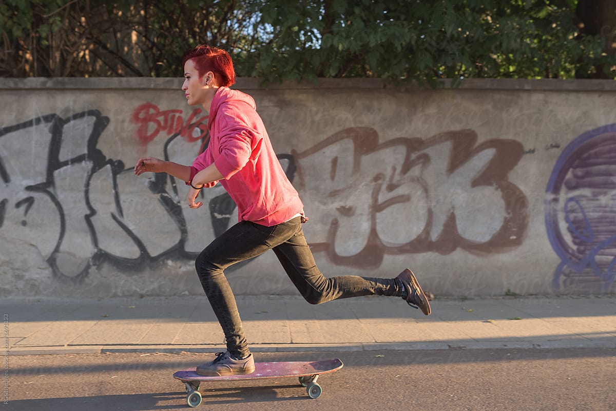 Redhead female skater skateboarding in urban scenery