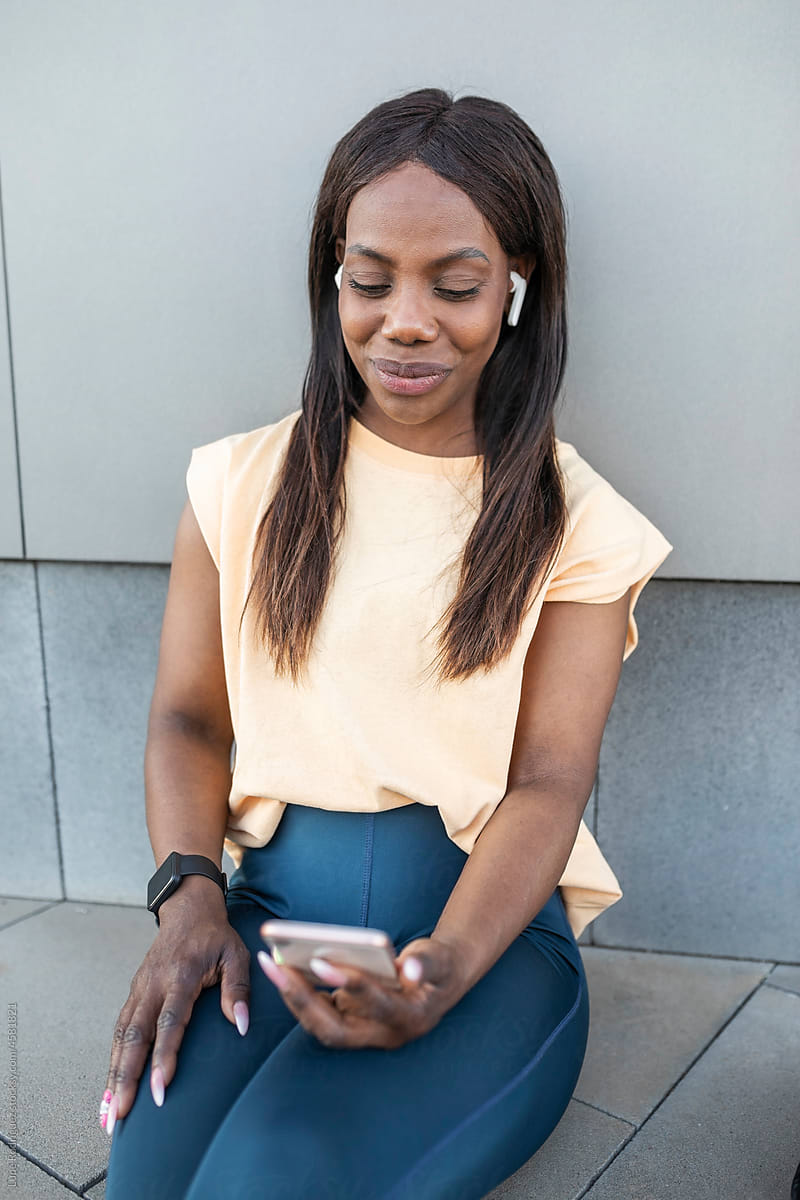 Black woman listening to music with mobile phone outdoors
