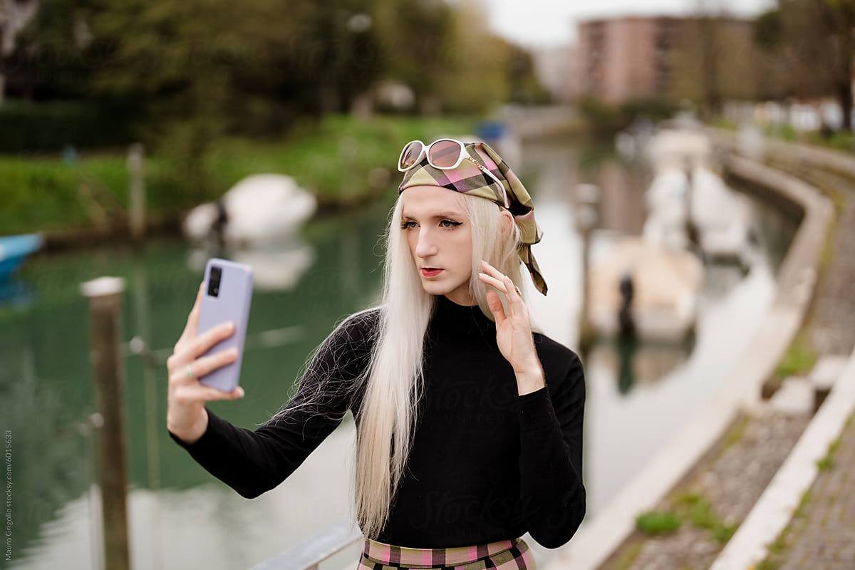 A stylish blond man using a smartphone for a selfie