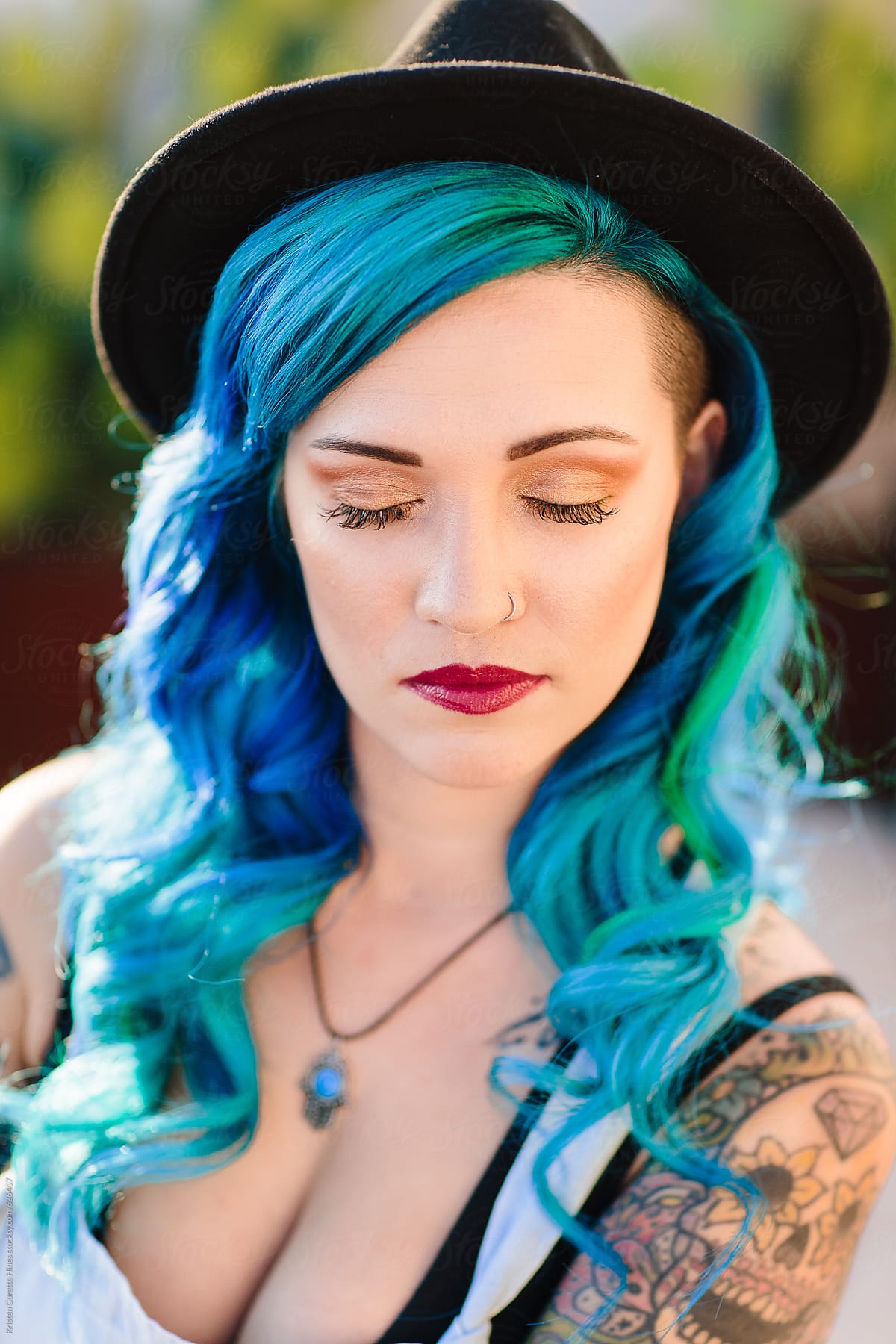 Vertical portrait of a beautiful mixed ethnicity women with blue dyed hair and a nose ring.