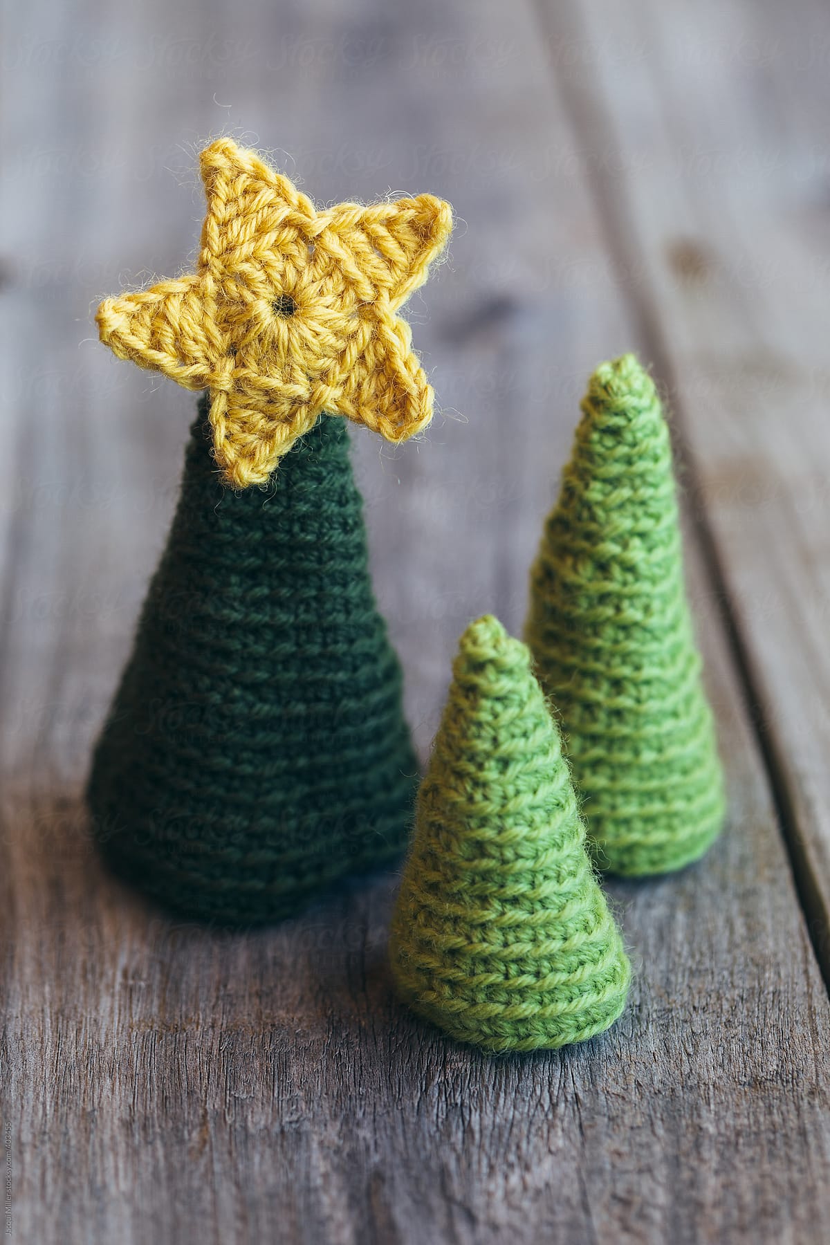 Close up of three crocheted christmas trees on a wooden background