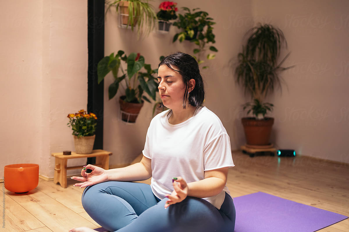 Woman meditating in a cozy room after a yoga class