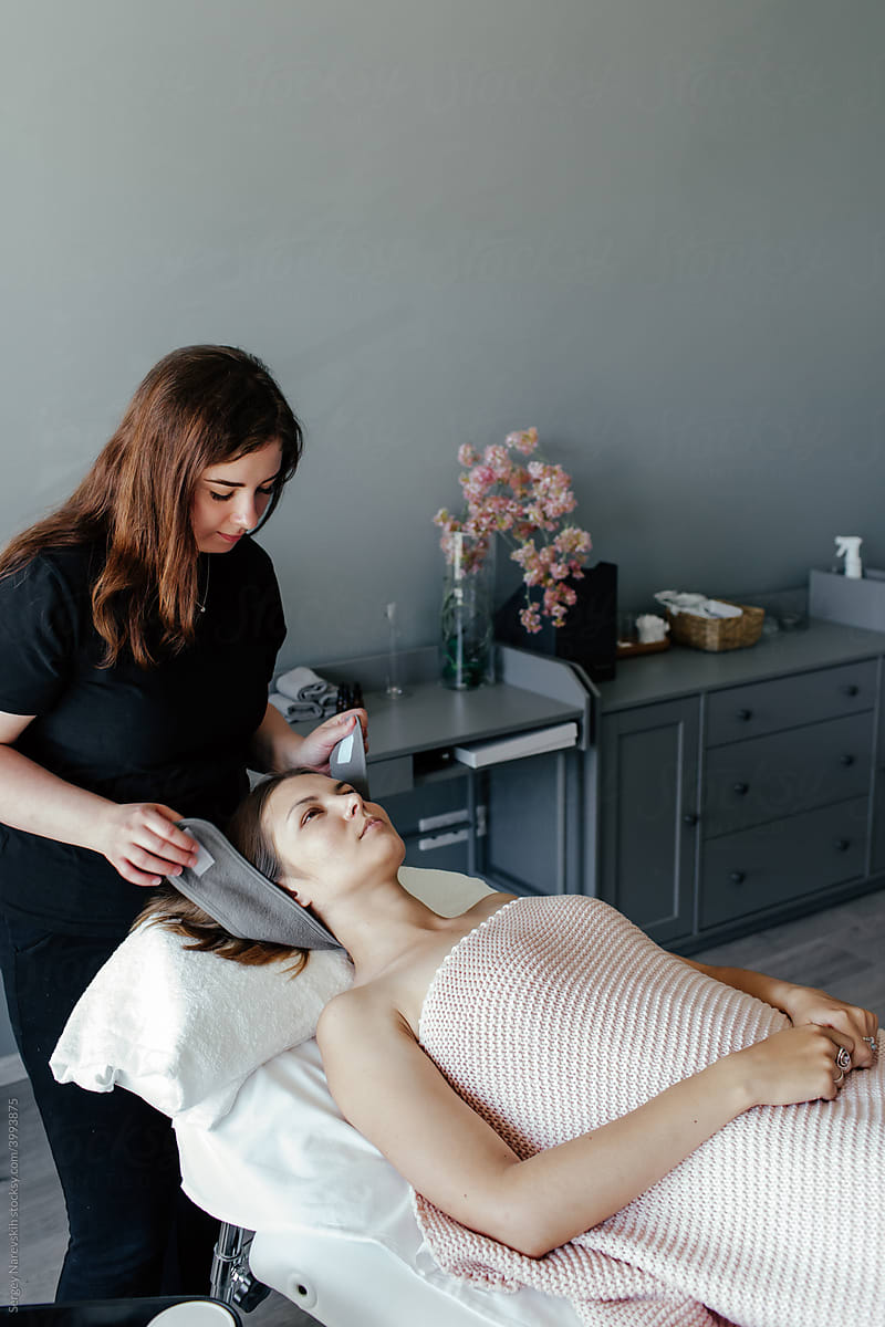 Female beautician preparing client for skin care procedure