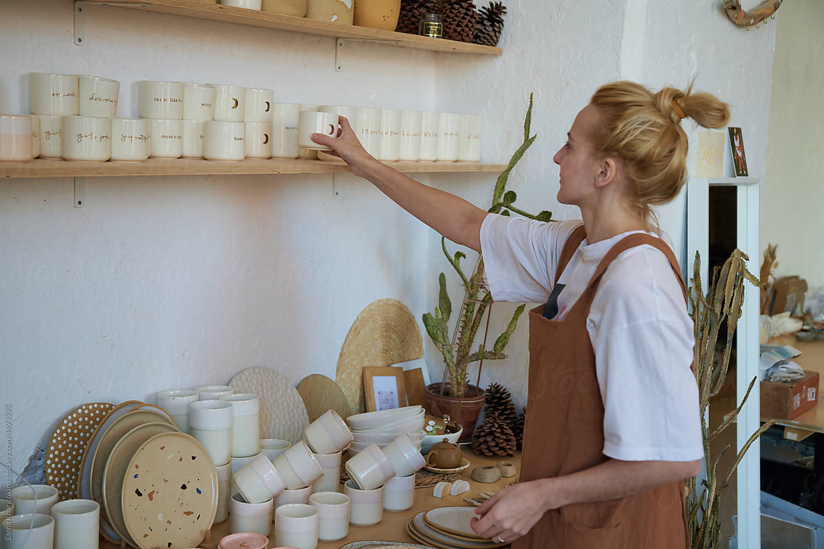 Female Ceramist puts finished products on the shelf