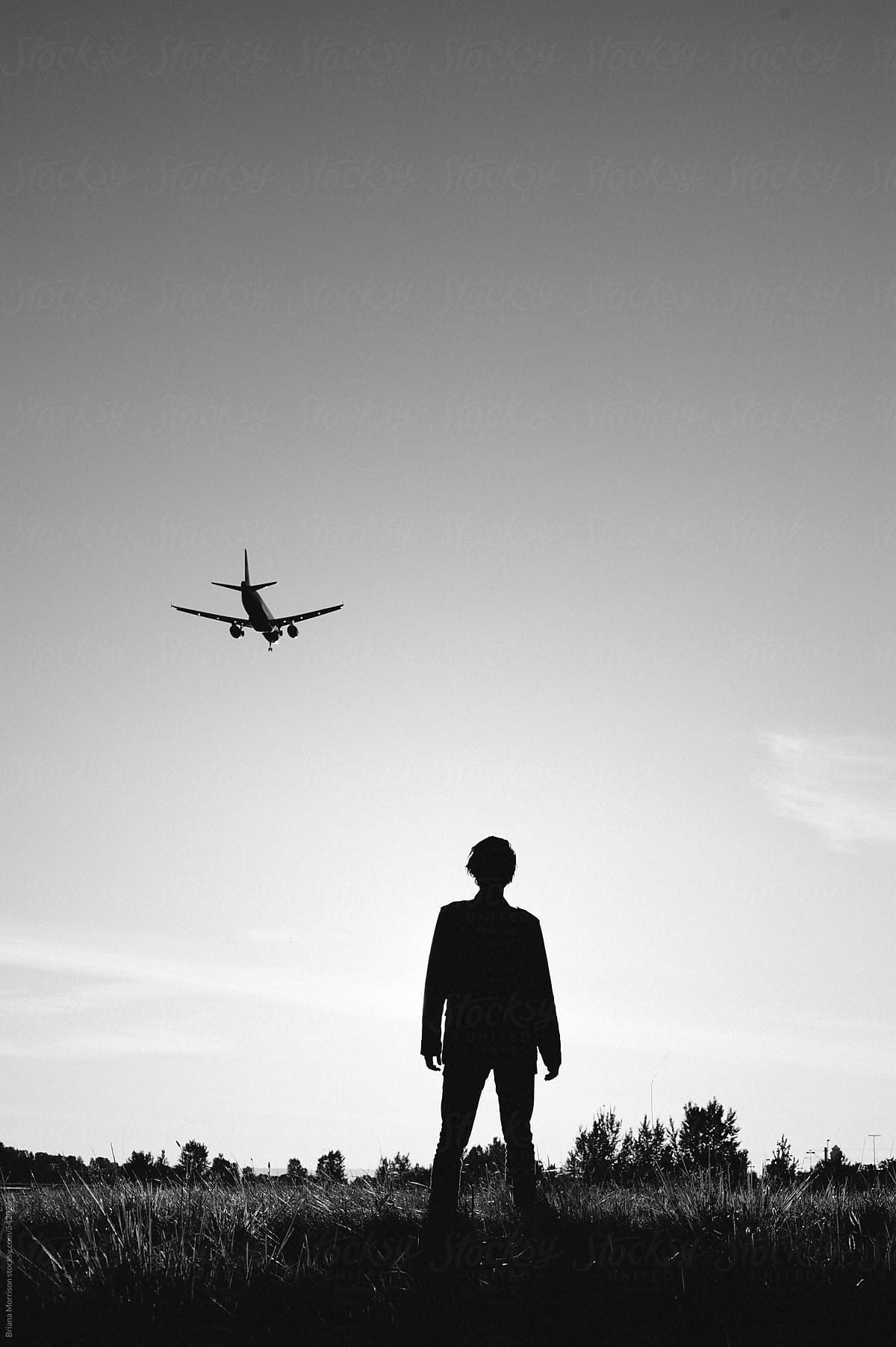 Silhouette of a Man Watching a Plane in the Sky in Black and White
