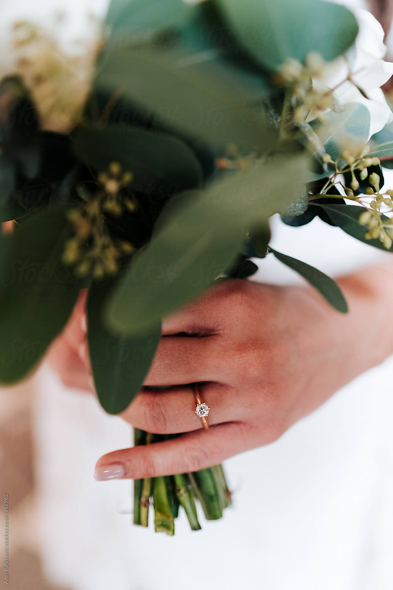 Close up on the hand of a bride with a bridal bouquet