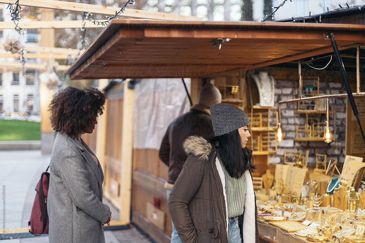 Young people looking at the stalls of an outdoor market in winter