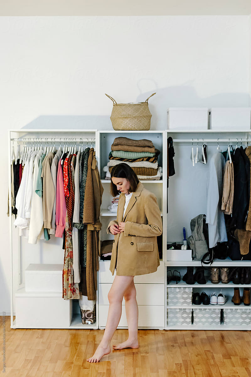 Woman standing in stylish jacket near wardrobe