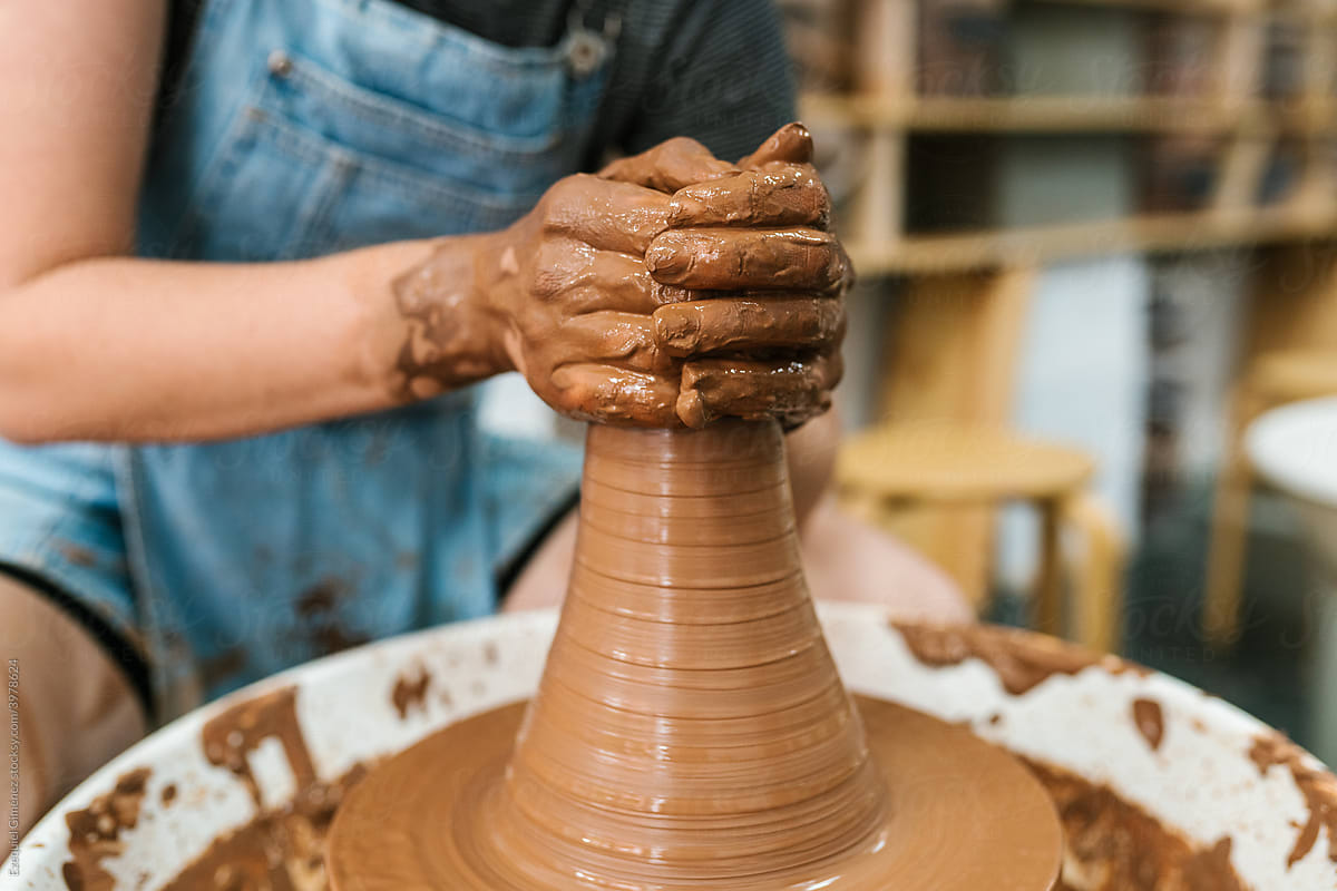 Craftswoman and making a clay pot on the potter\'s wheel
