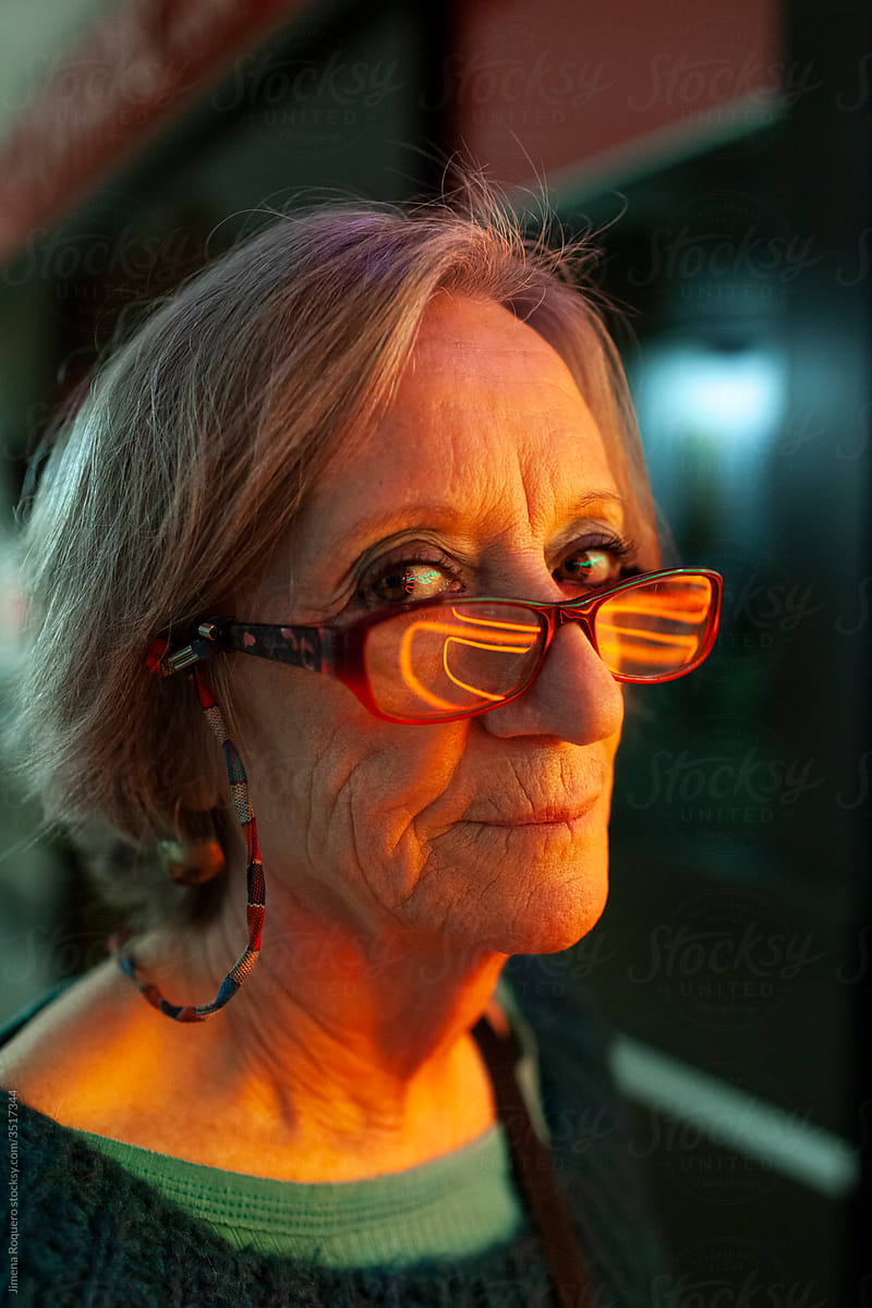 Portrait of elderly woman on neon lights looking at camera