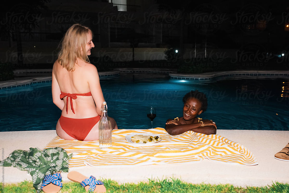 Funny women talking at poolside at night
