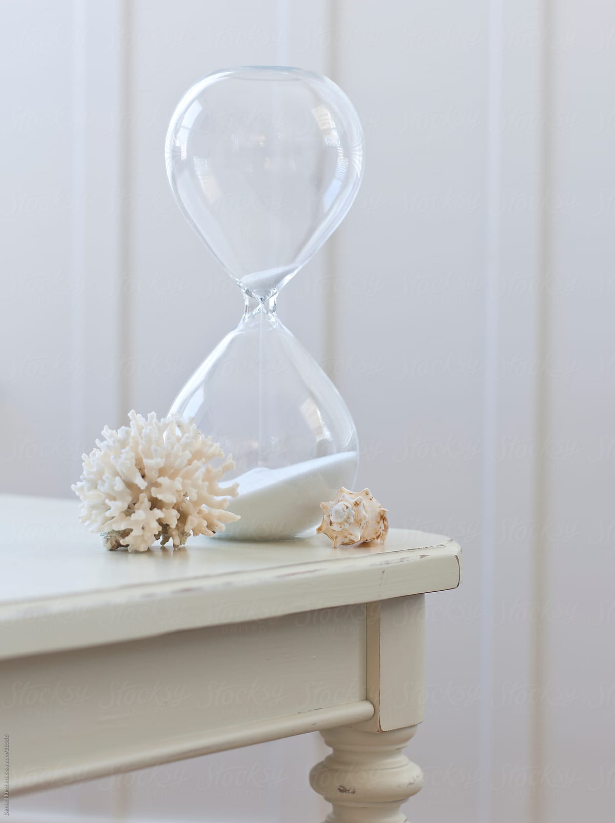 Hourglass, coral and shell on table