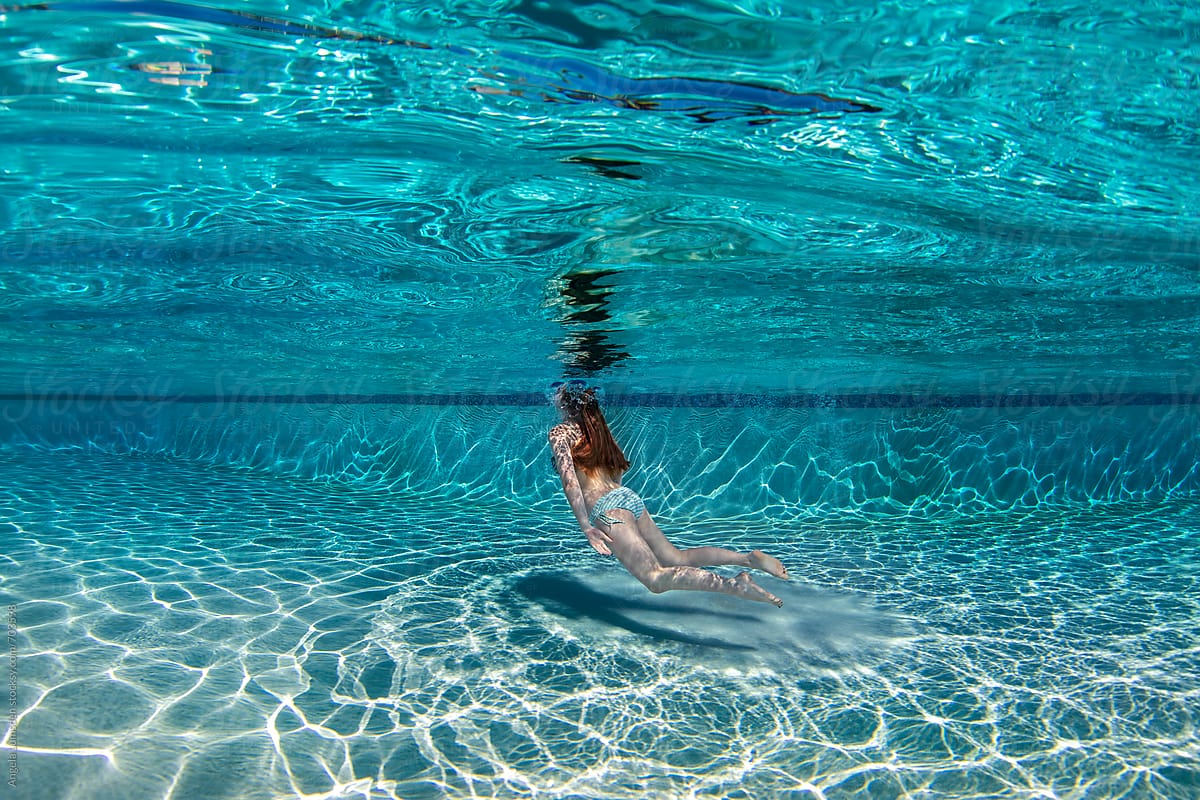 Teenage Girl Floating Underwater In A Large Deep Blue Swimming Pool By 