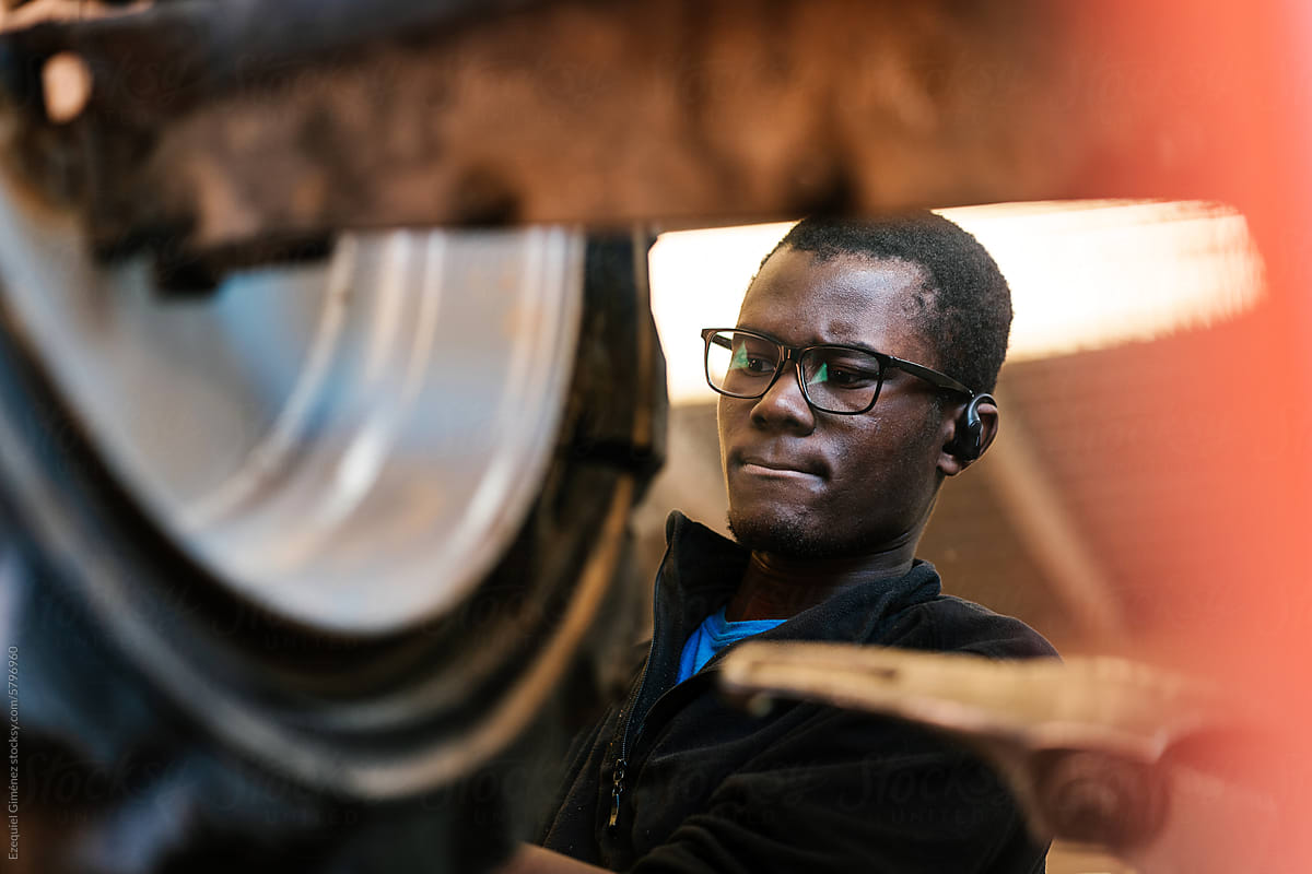 Black mechanic repairing car wheel