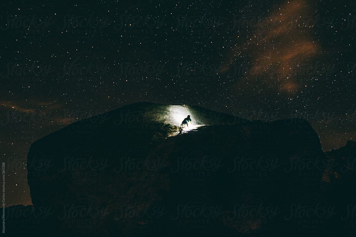 Night climbing - Man climbing a huge boulder at night with a headlamp