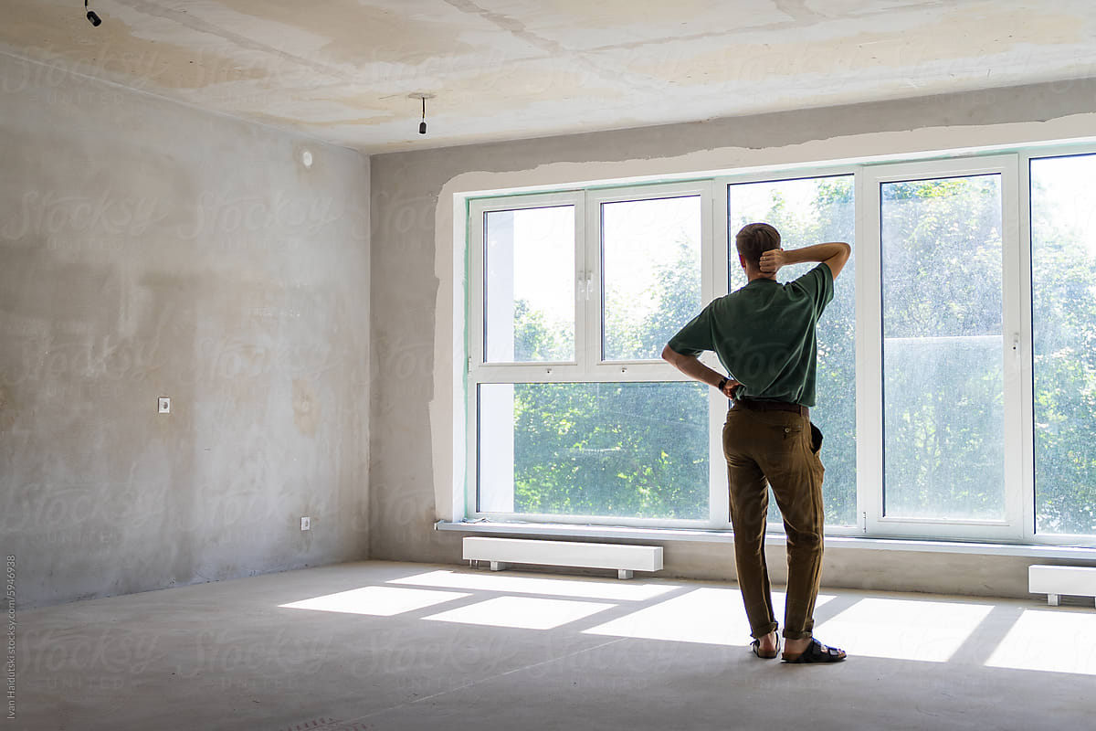 millennial man in front of big window in a new home apartment