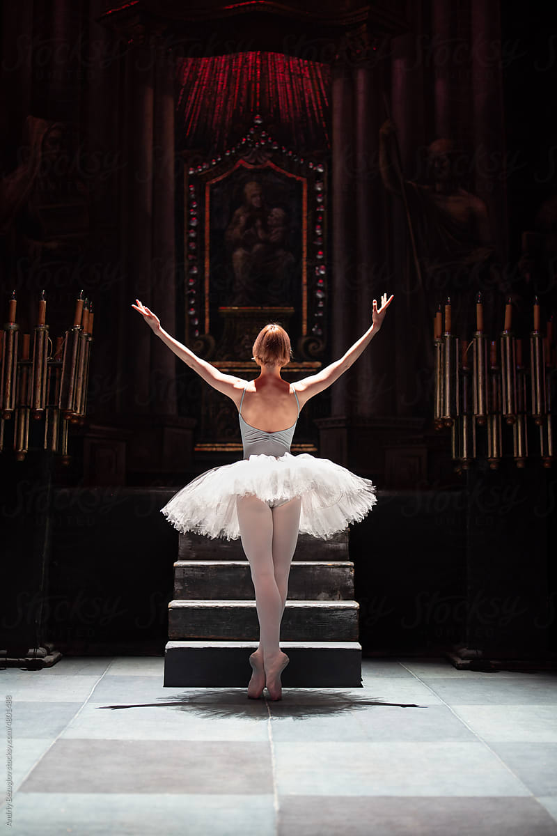 Back view of ballerina standing with her hands up