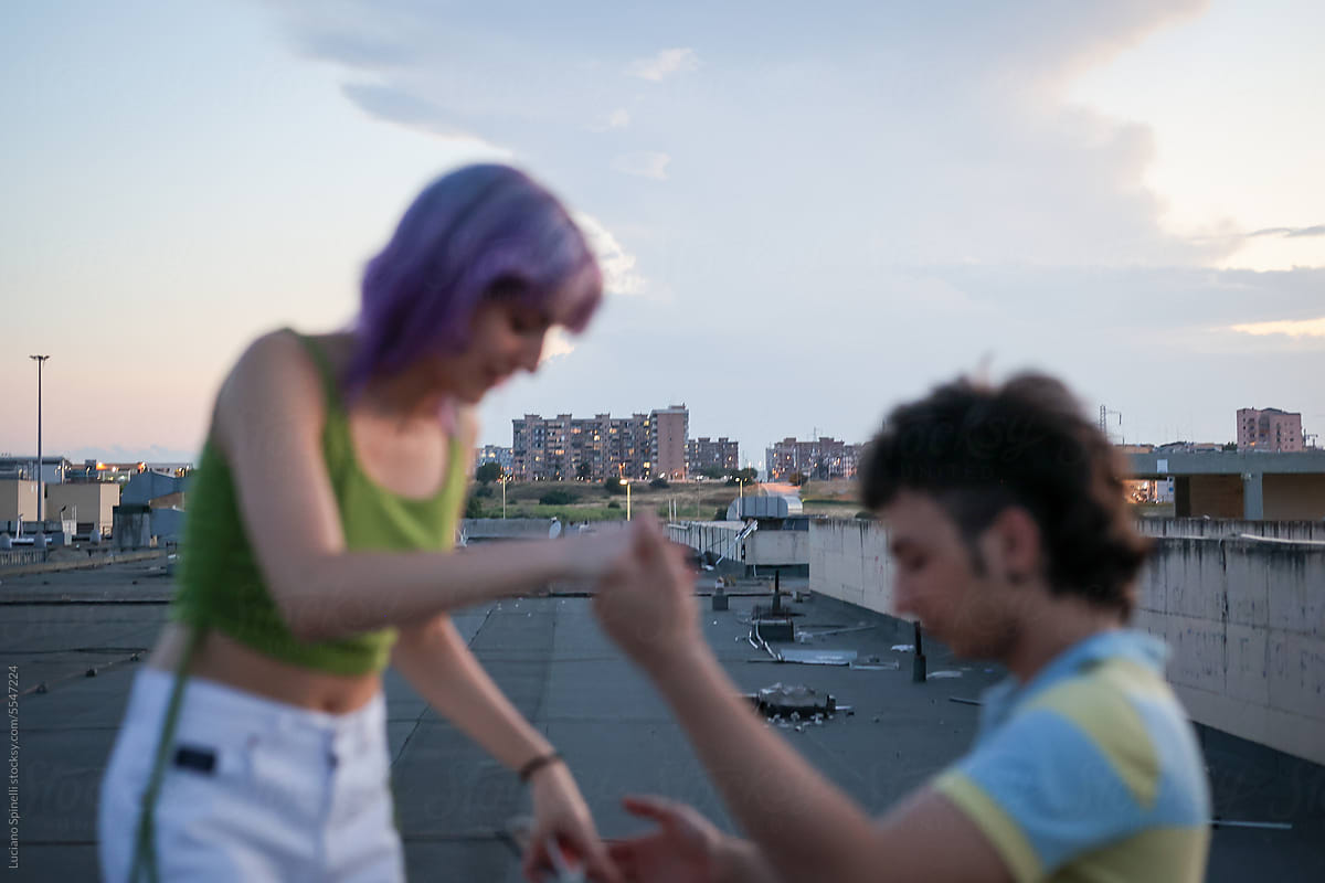 Blurred Gen Z friends dancing and having fun during sunset on rooftop