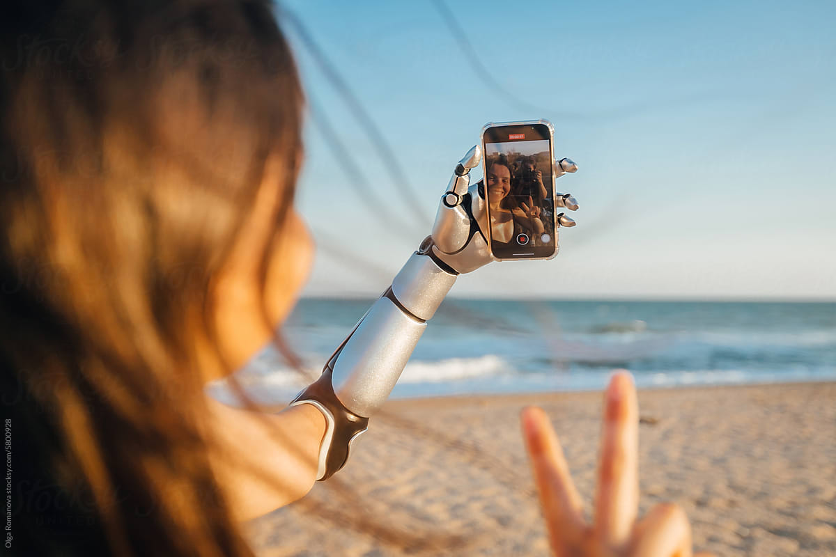 Smiling woman with arm prosthesis making selfie with phone