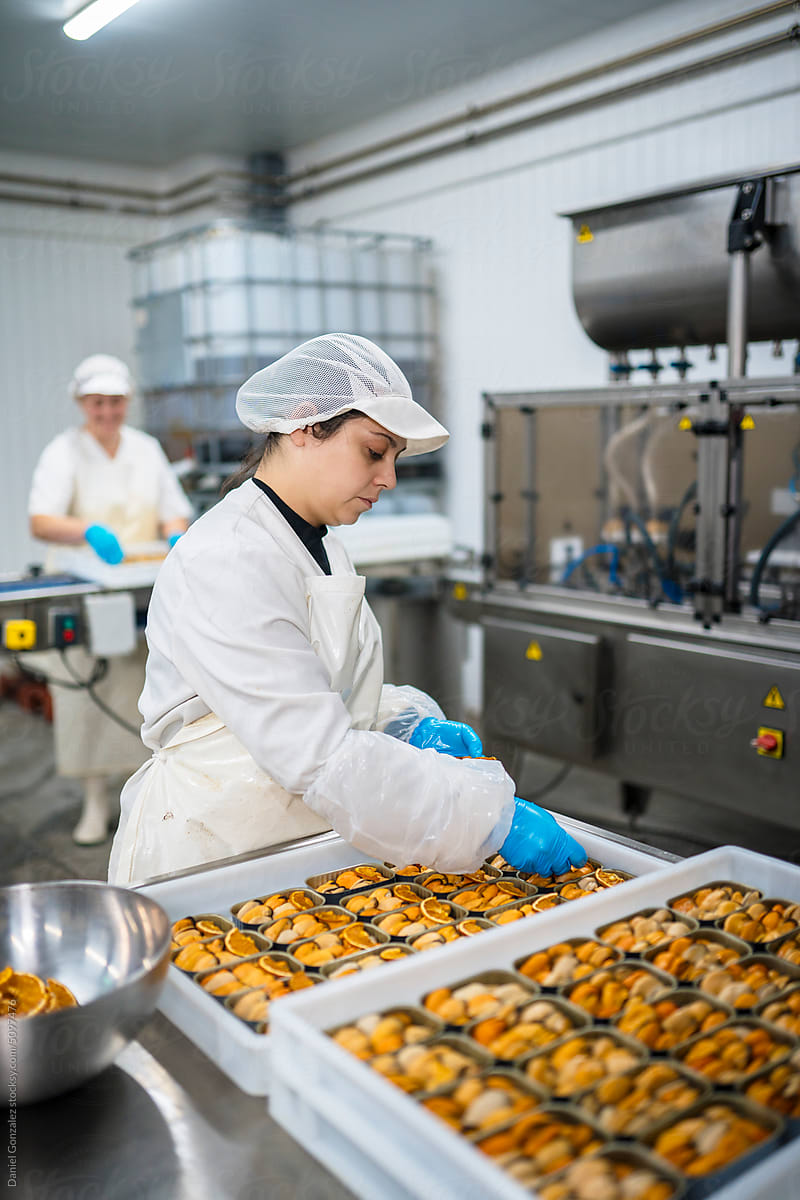 Hispanic worker adding citruses to canned mussels