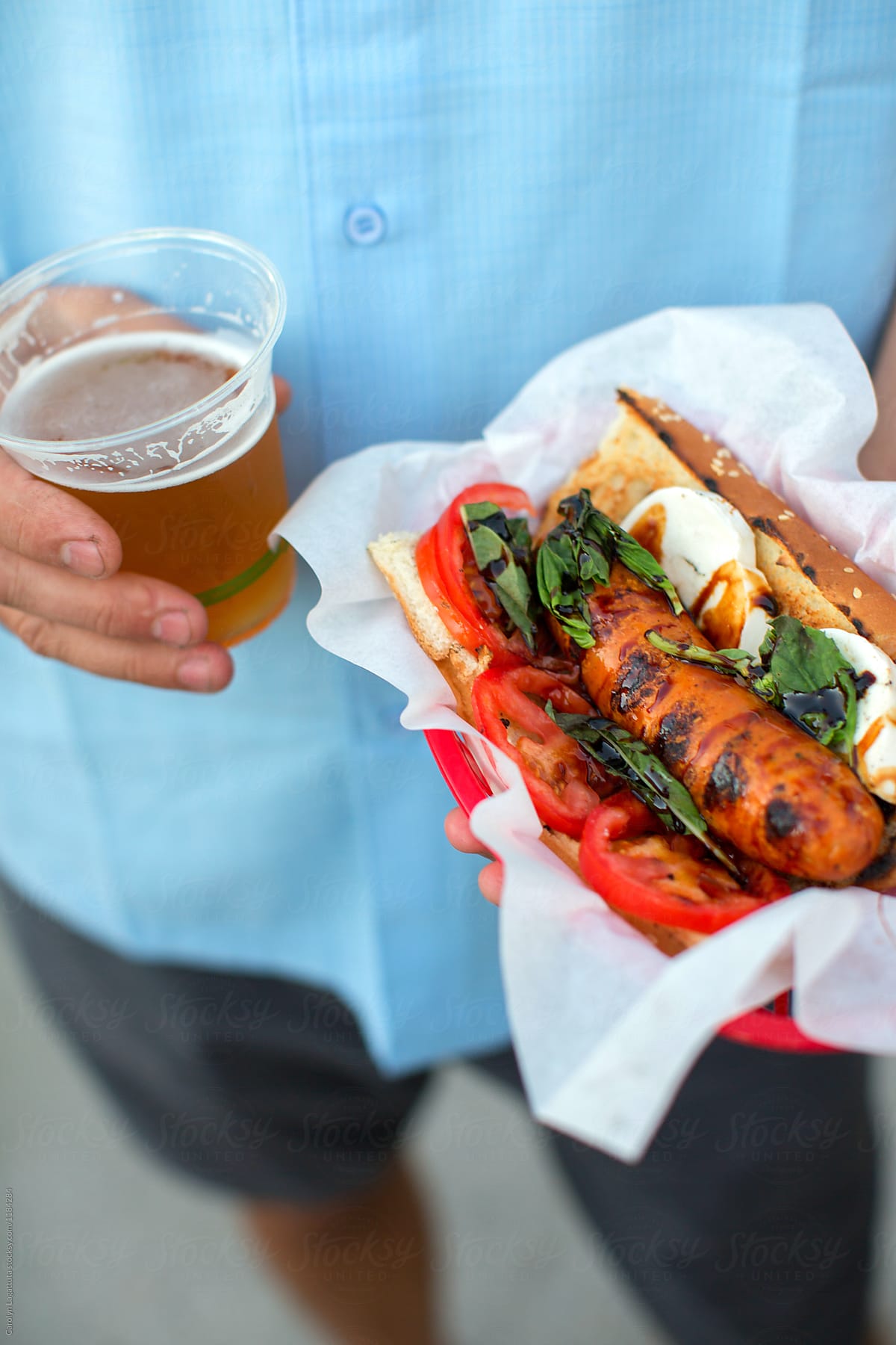 Man holding a caprese hot dog and a pale ale draft beer