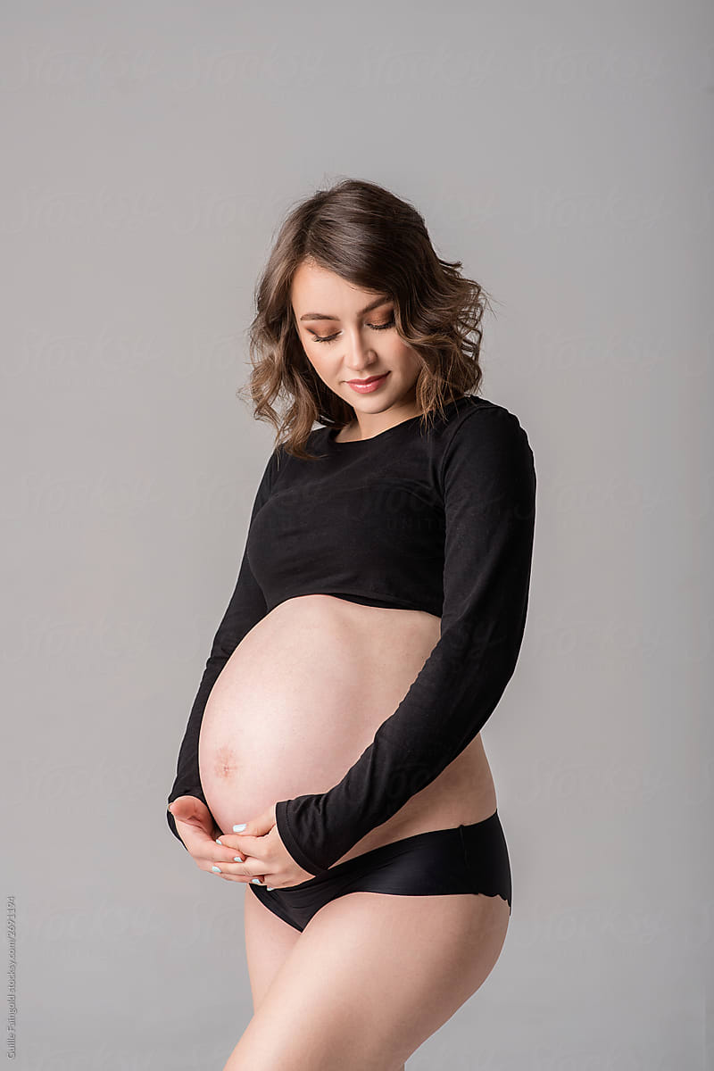 Beautiful pregnant woman embracing her belly.