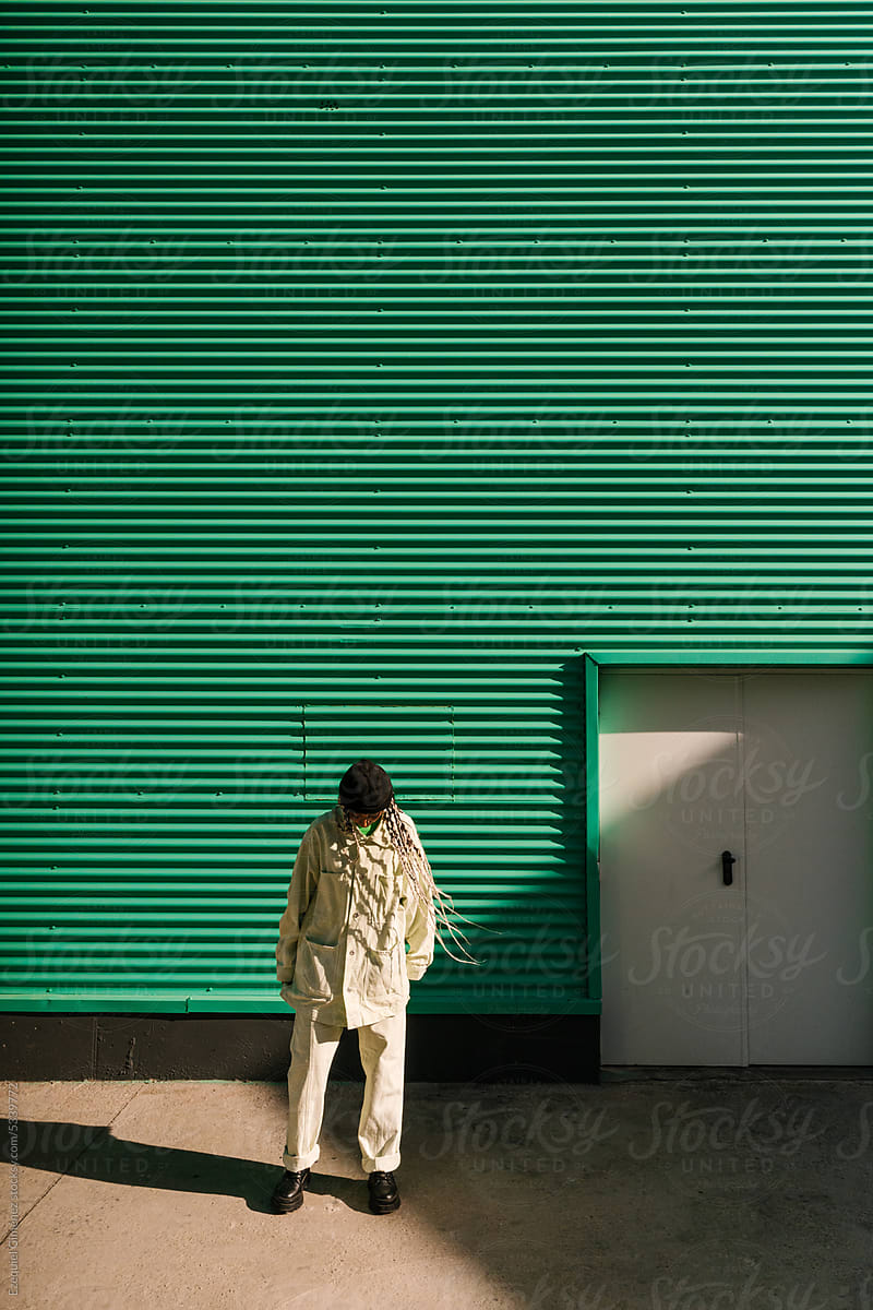 Stylish woman standing near green wall