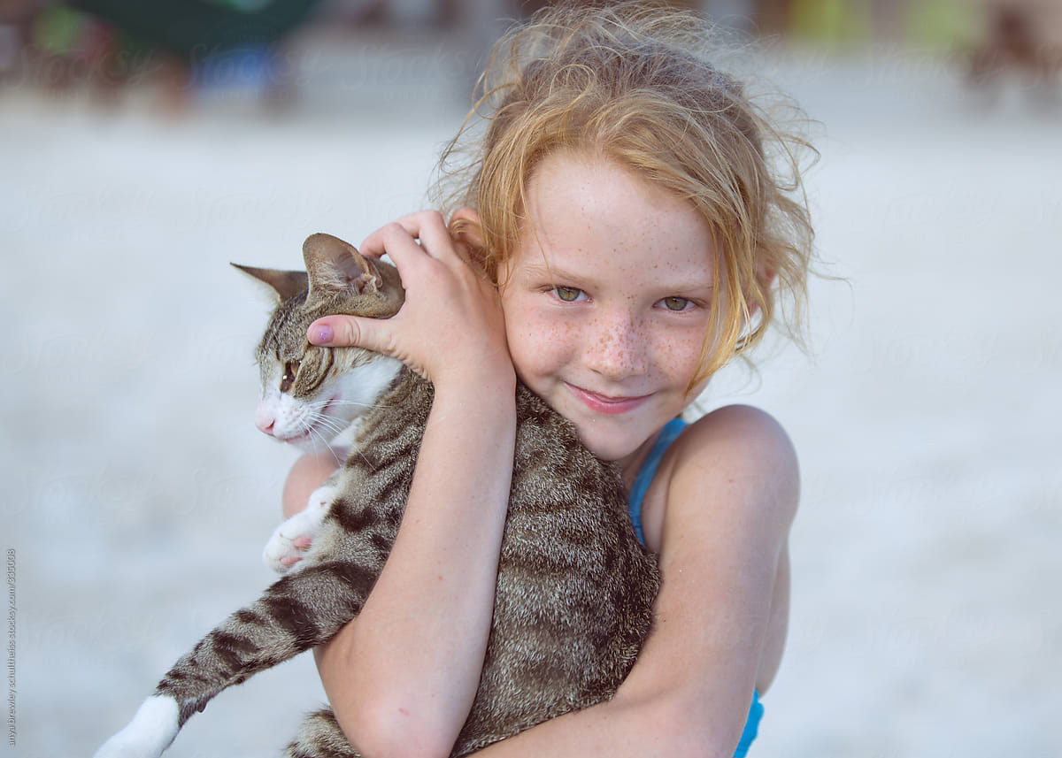Young girl with blond hair holding a cat lovingly