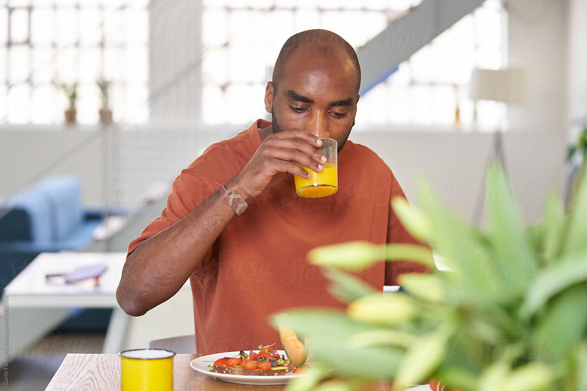 Black man drinking juice during breakfast