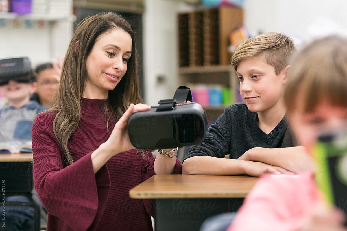 Classroom: Teacher Instructs Boy On How To Use VR Headset