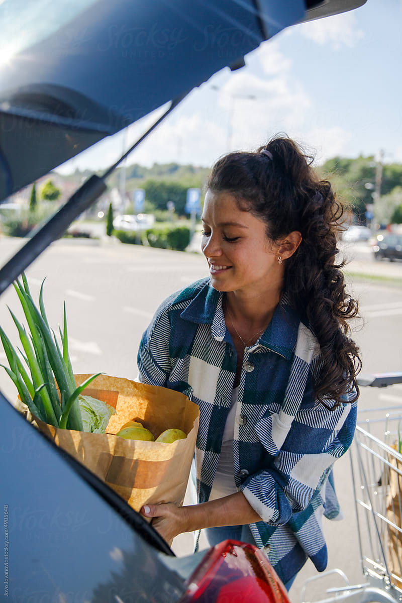 Woman loading groceries into car trunk
