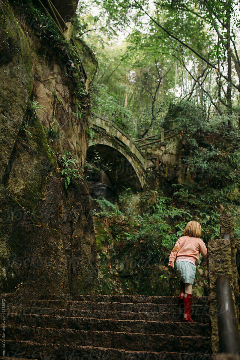 Young girl walks up stone steps in the forest