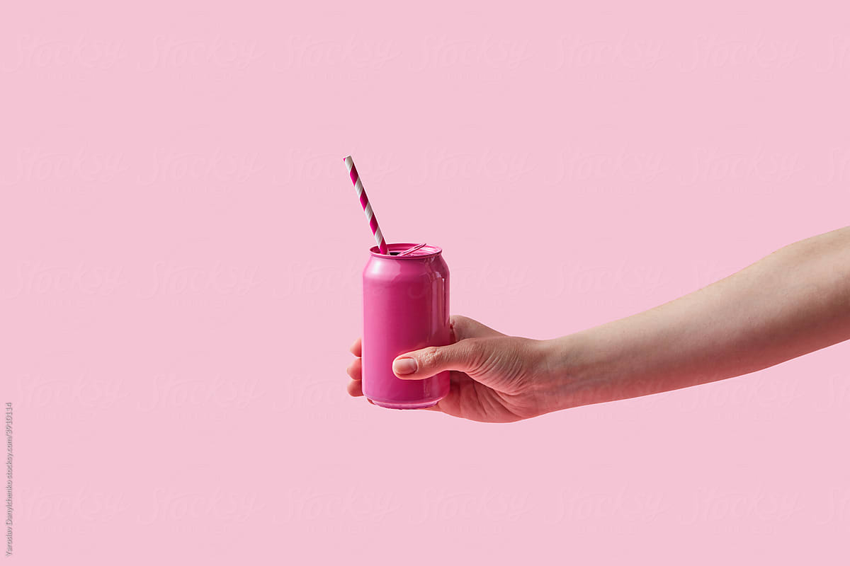 Woman holding pink soda can with paper straw
