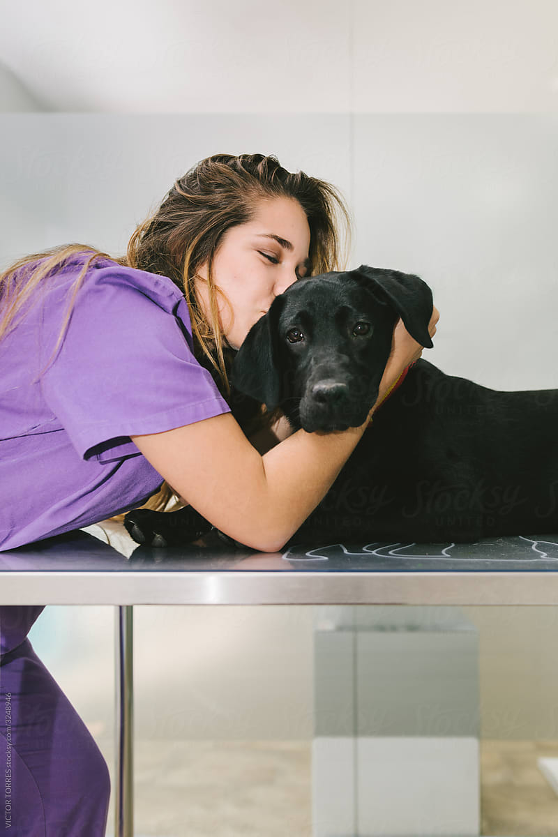 Happy nurse kissing a dog in the vet clinic