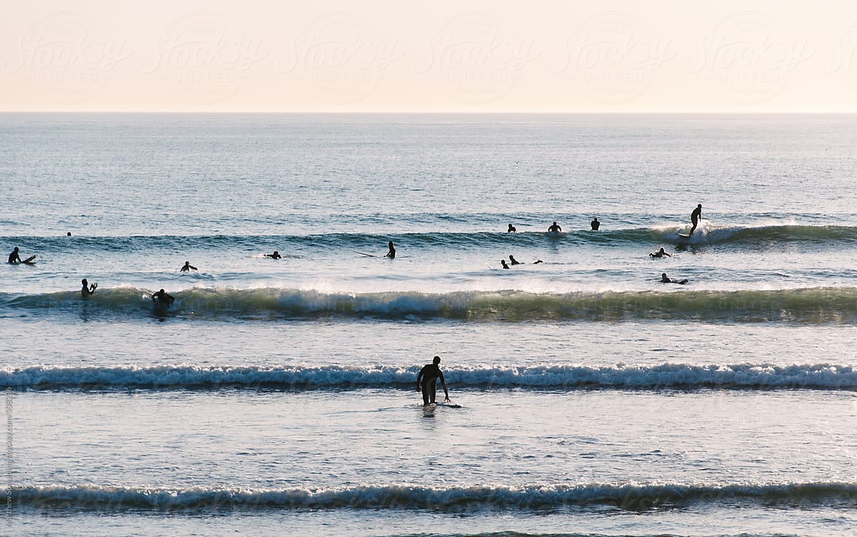 Many surfers paddling riding and surfing in ocean waves on beach