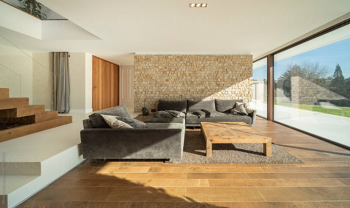 Modern living room with big windows. Ceramic, wood and stone materials