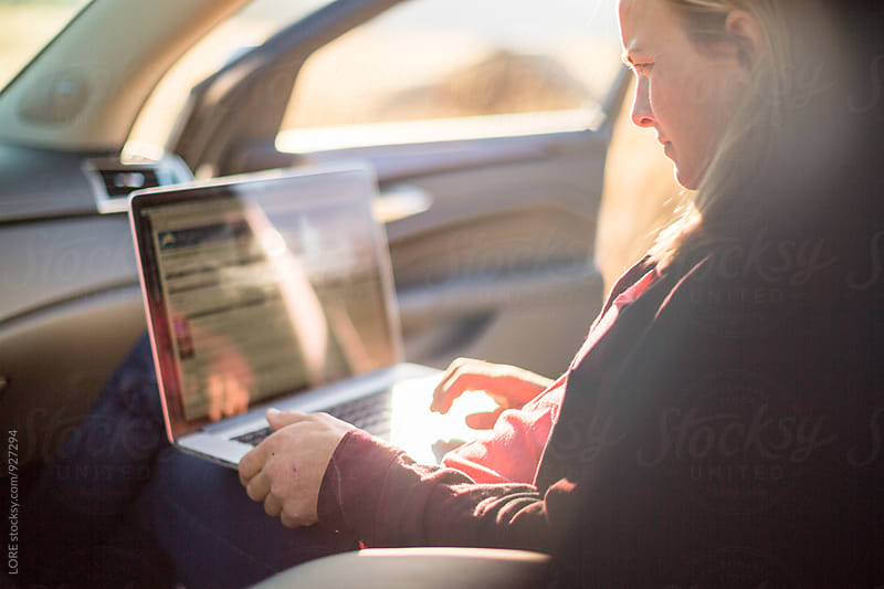 Young Adult Woman uses a computer in the passenger seat of a car