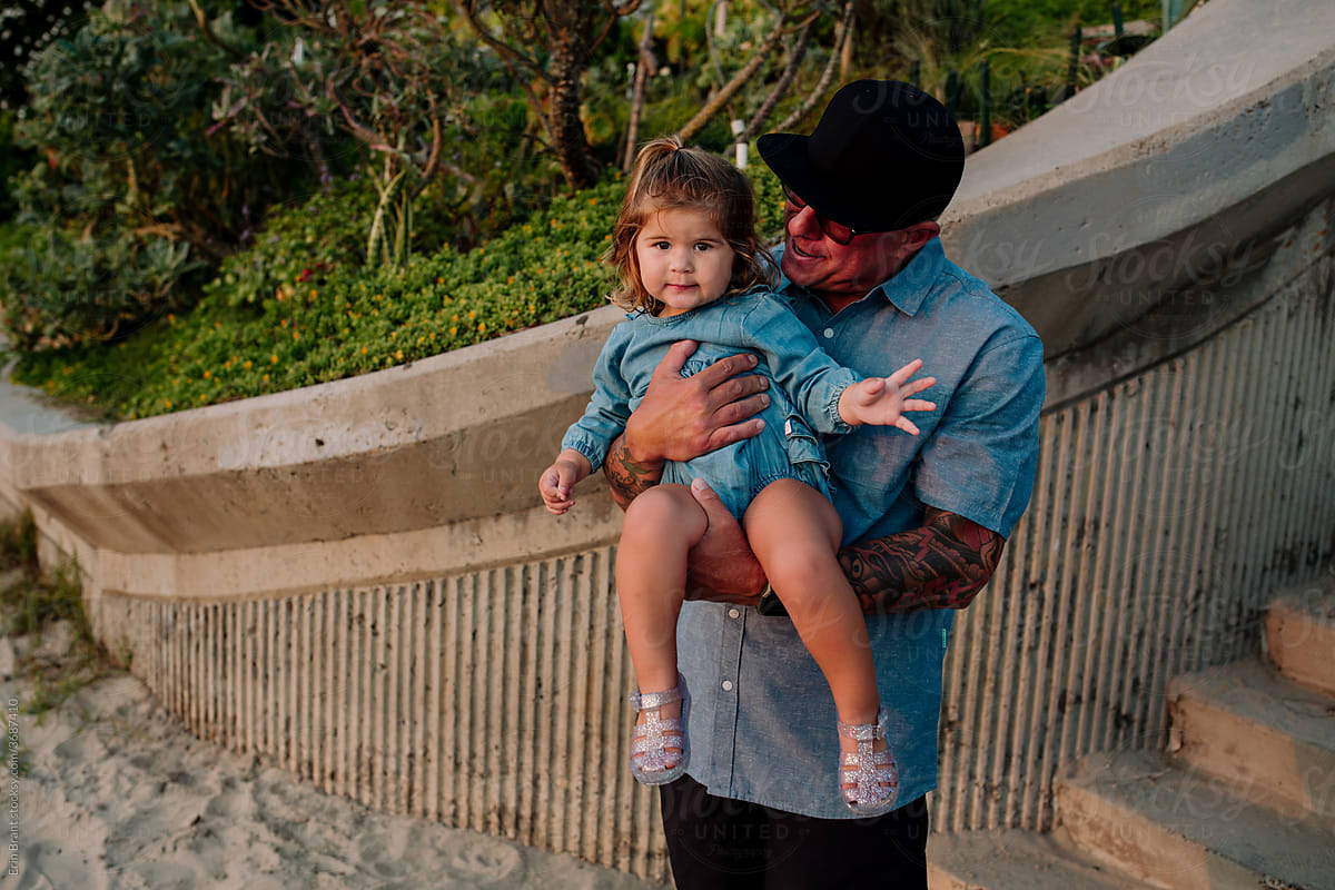 Dad holding daughter near stairs to beach
