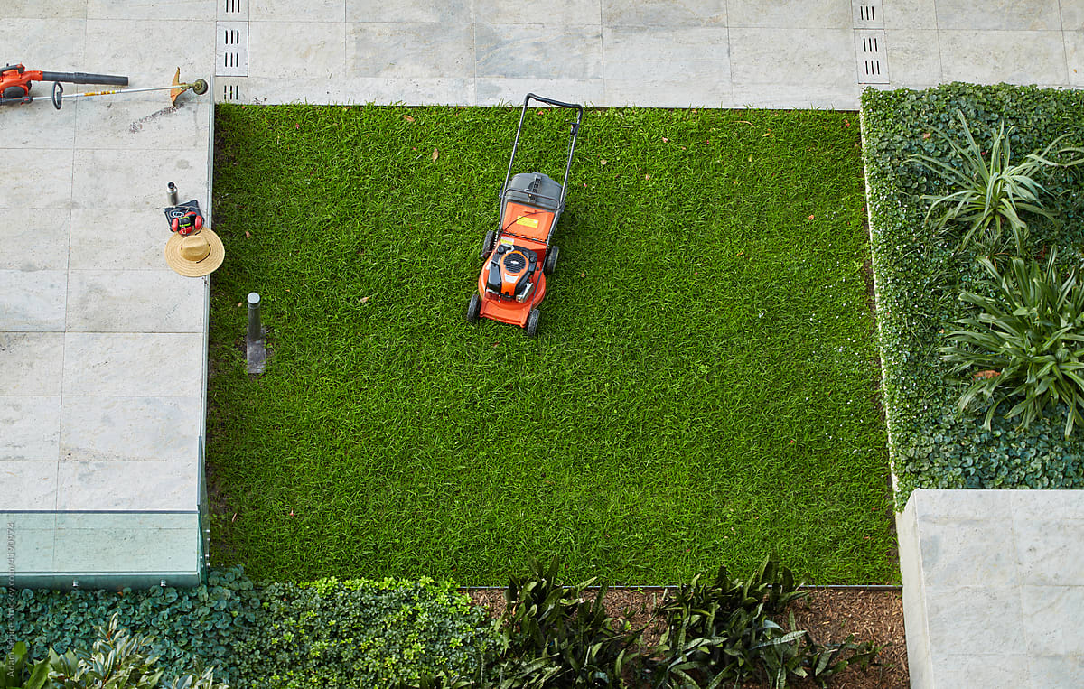 Lawn mower, concrete, patch of green grass - urban greenery symmetry