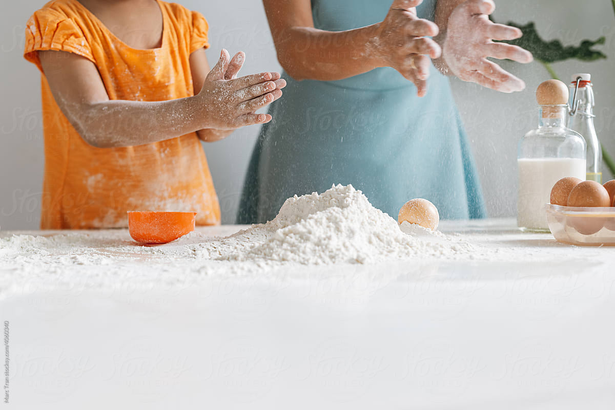 Mother teaching daughter prepare dough together in kitchen