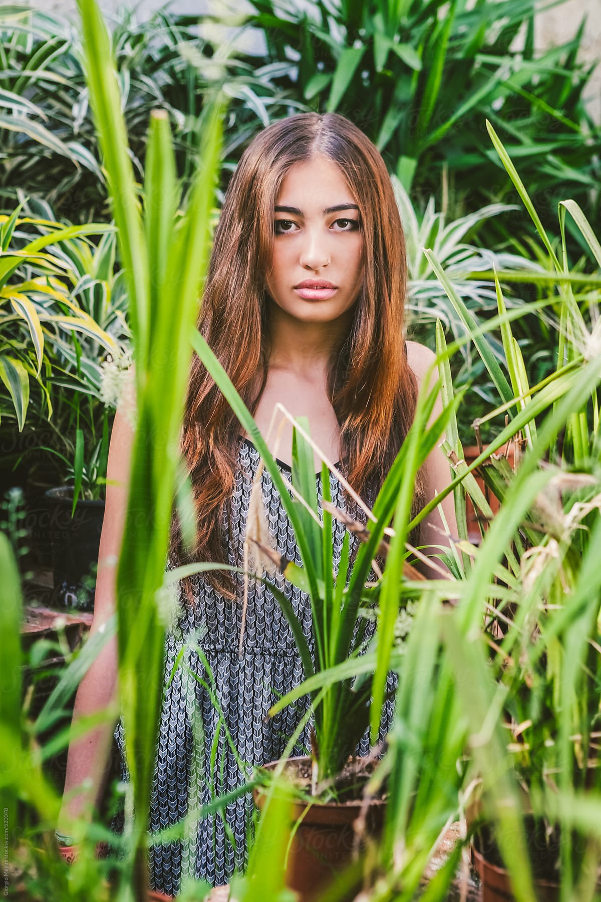 Young Asian Model Hiding Between Plants in a Greenhouse