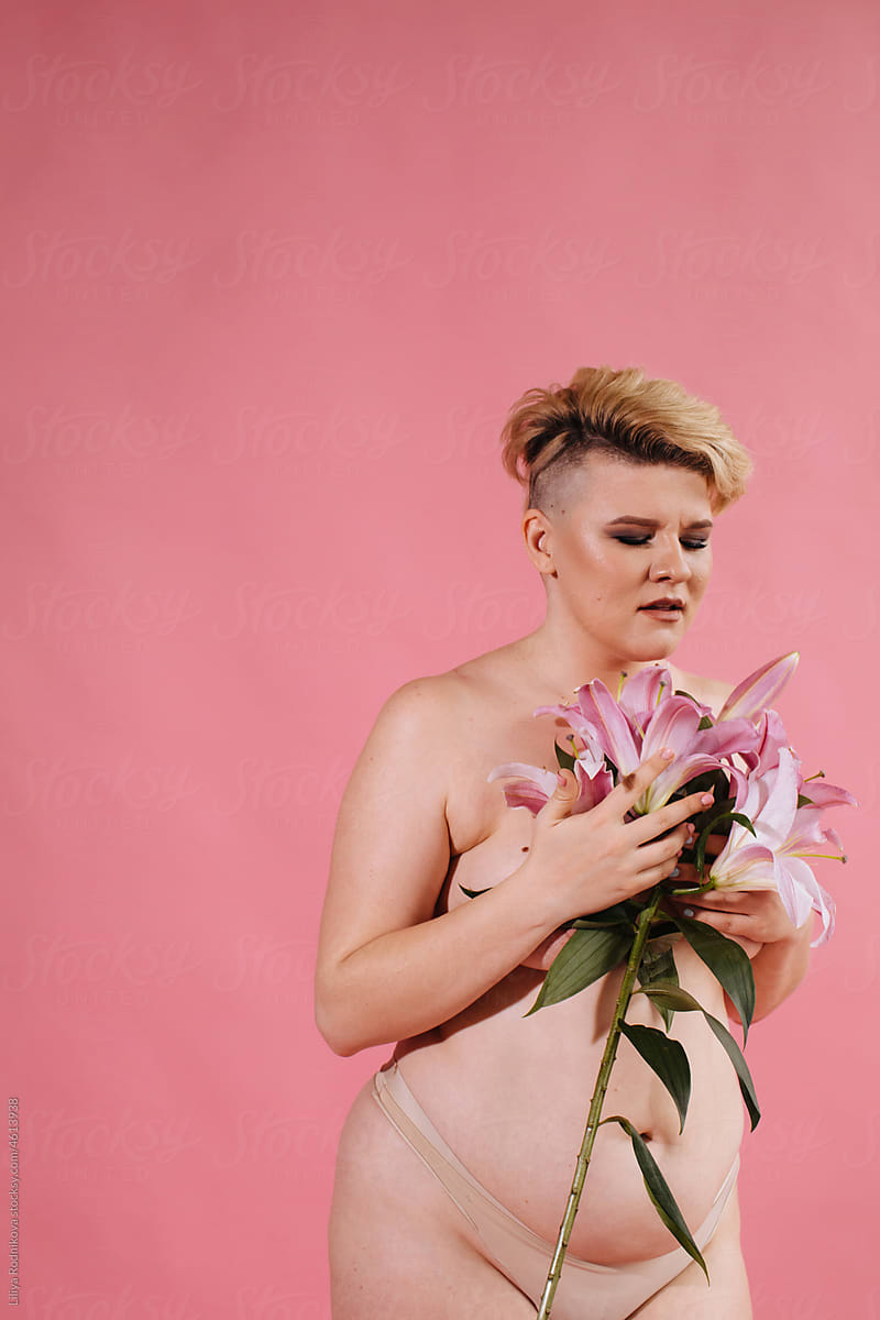 Woman with short blond hair posing with pink lilies
